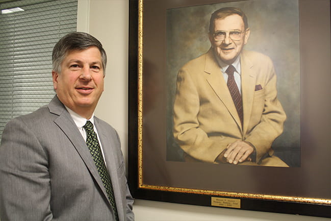 Dean Hall stands next to the portrait of Michael P. Araneo 
