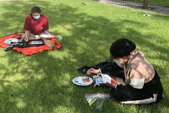Emily Overly and Shayma Alzaidi  painting on the lawn
